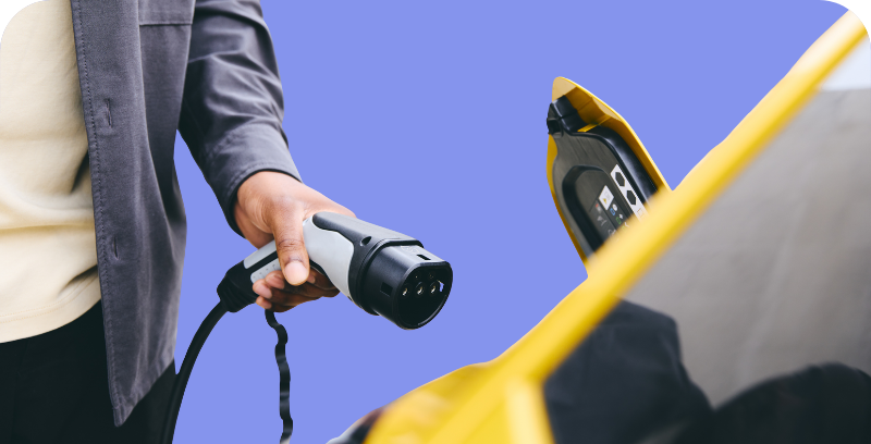 Cilvēks pievieno lādētāju pie elektroauto